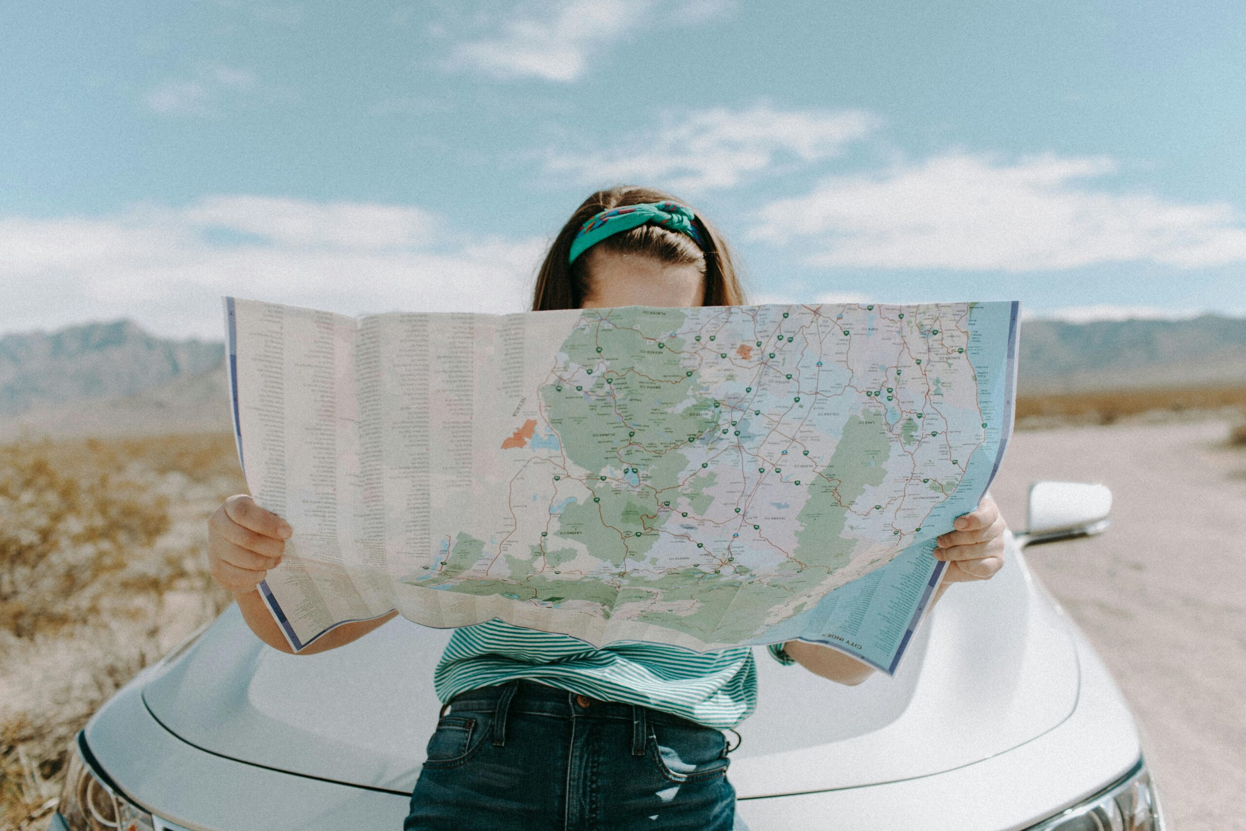 A woman holds a map while traveling through the scenic desert of California, USA.